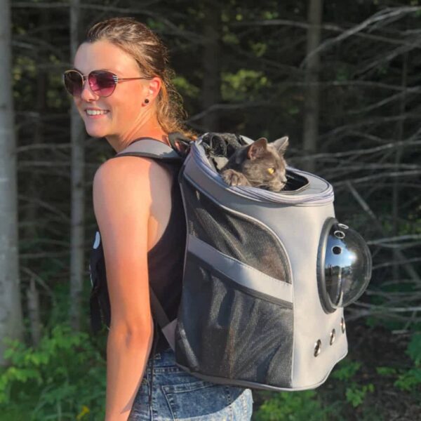 girl carrying fat cat backpack hiking woods